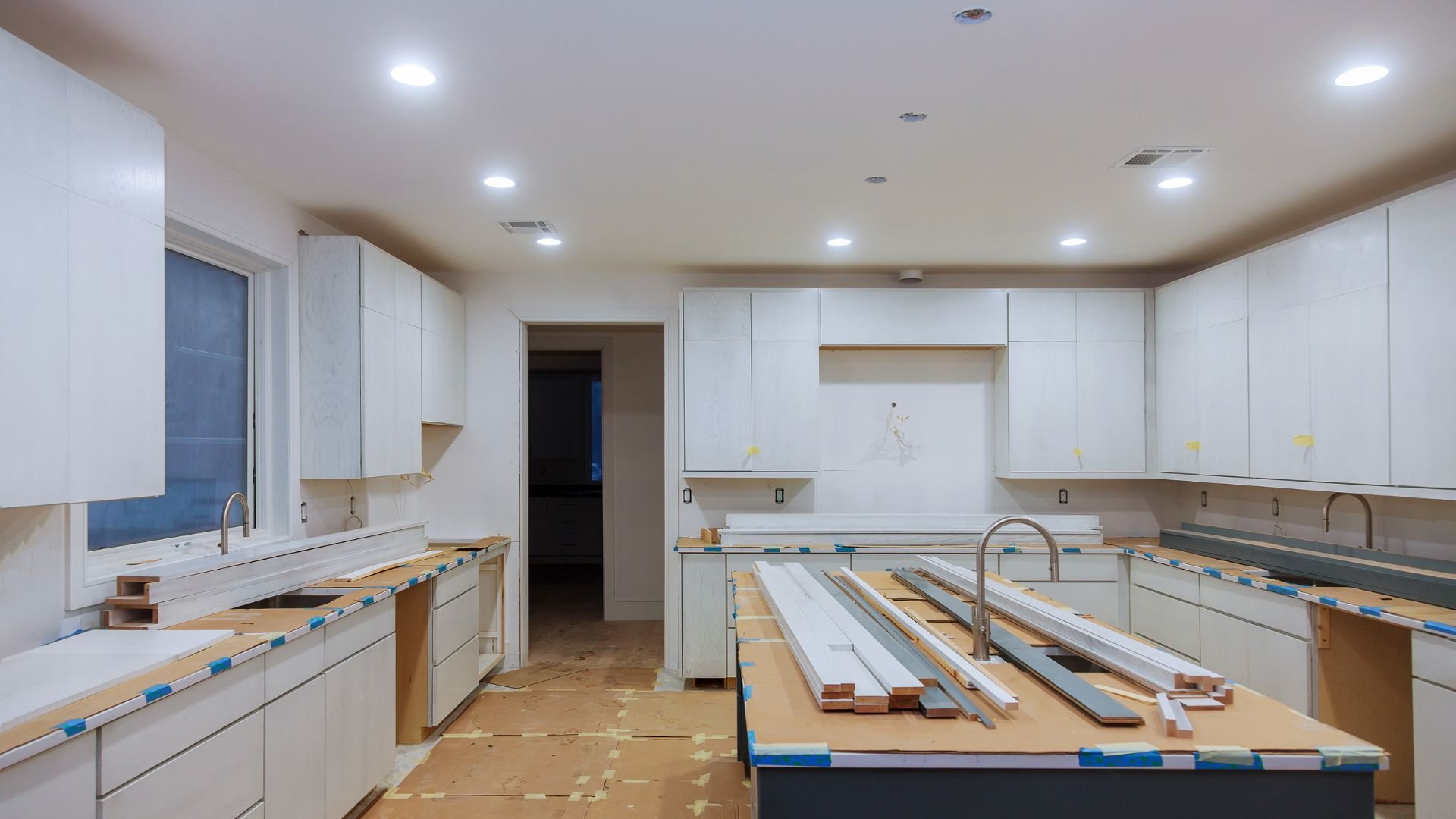 Kitchen renovation in progress with white cabinets and construction materials