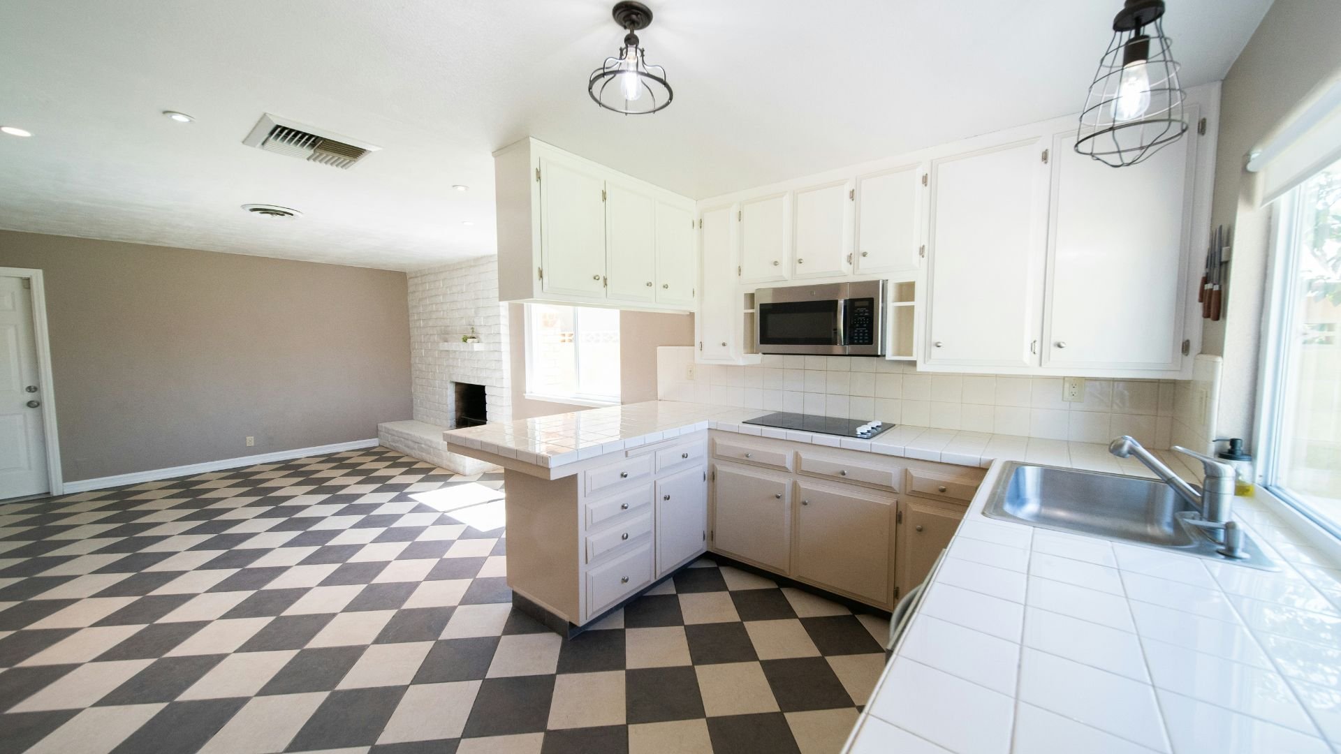 Bright kitchen with white cabinets, black and white checkered floor, microwave