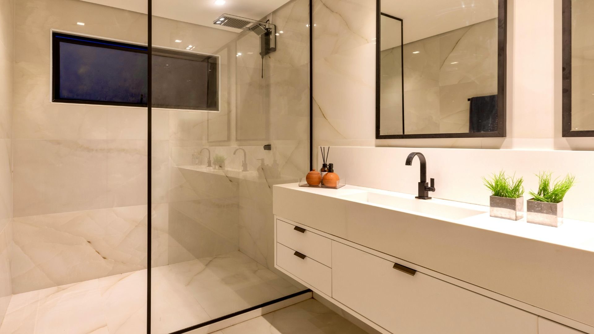Modern bathroom with marble walls, glass shower, and white vanity